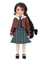 Doll wearing a plaid dress and cardigan on a white background
