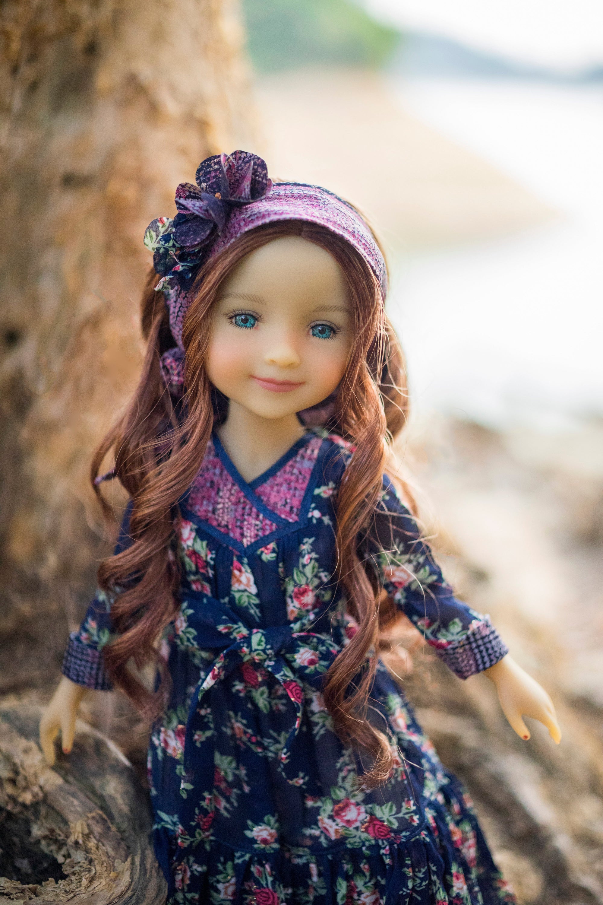 Doll with long brown hair wearing a floral dress and purple headband against a natural background.