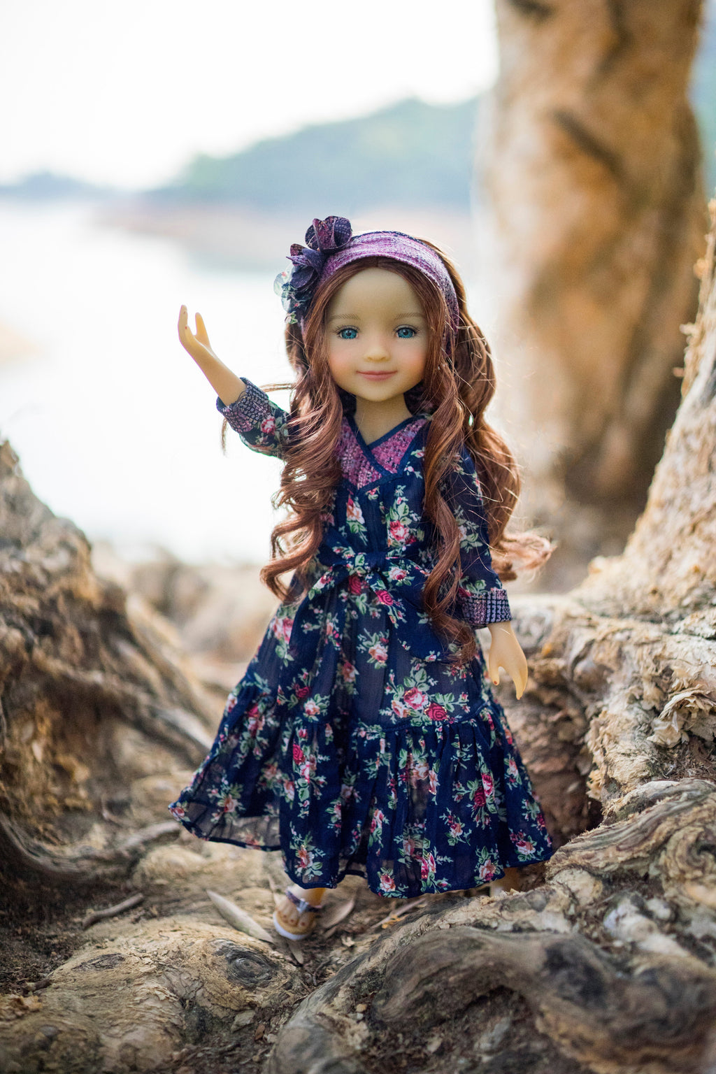 Doll in a floral dress standing on wooden logs with a natural background