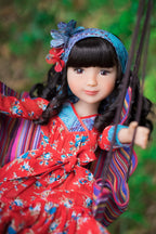 Doll in traditional outfit with red dress and blue headband against a blurred green background