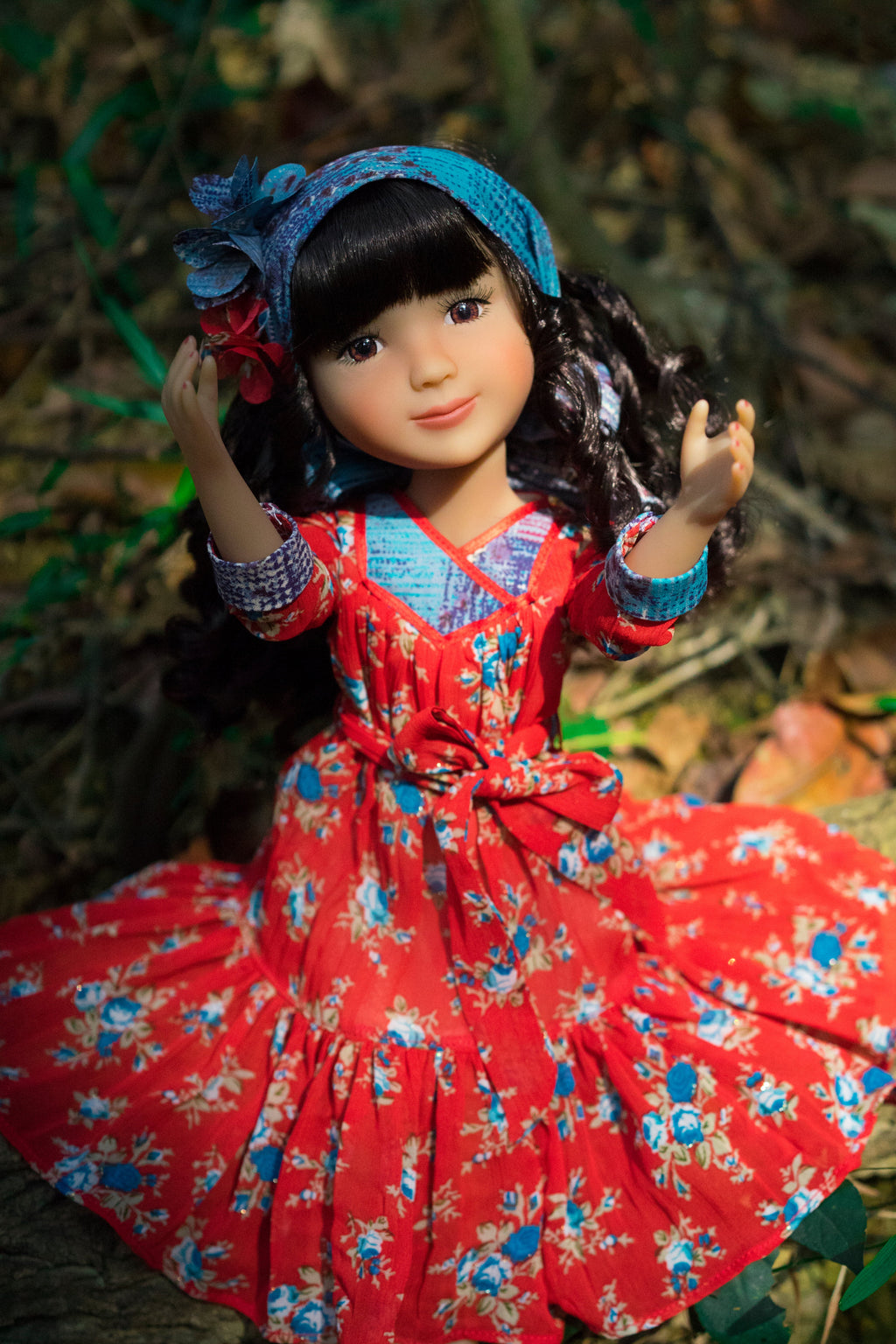 Doll in a red floral dress with a blue headband against a natural background