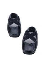 Black glittery doll shoes with criss-cross straps on a white background