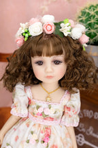 Doll with floral headband and dress in a decorative setting