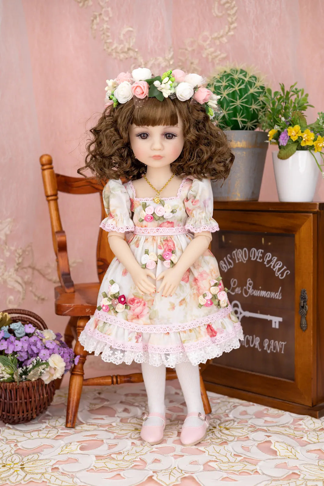 Doll in a floral dress with a flower crown standing in a decorative room.