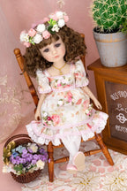 Doll in a floral dress sitting on a wooden chair with a decorative background