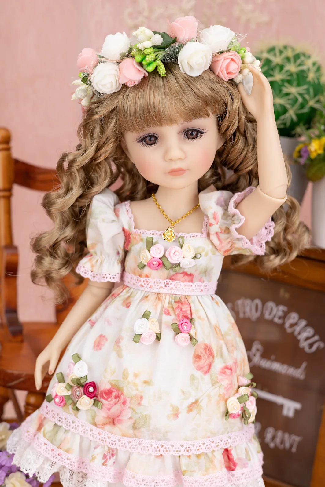 Doll in a floral dress with a flower crown against a blurred indoor background