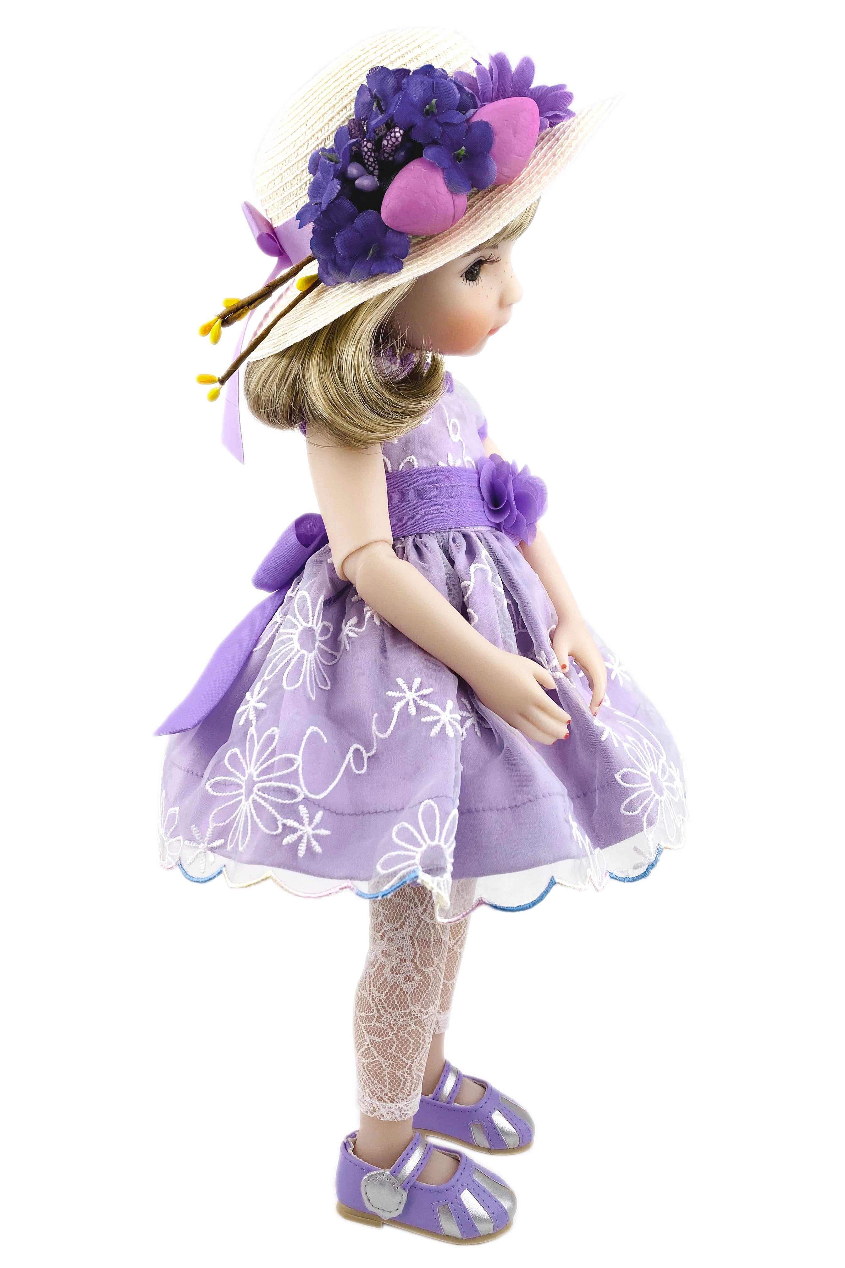 Doll in a purple dress with floral hat on a white background