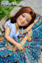 Doll with long brown hair wearing a blue dress and colorful patterned shawl.