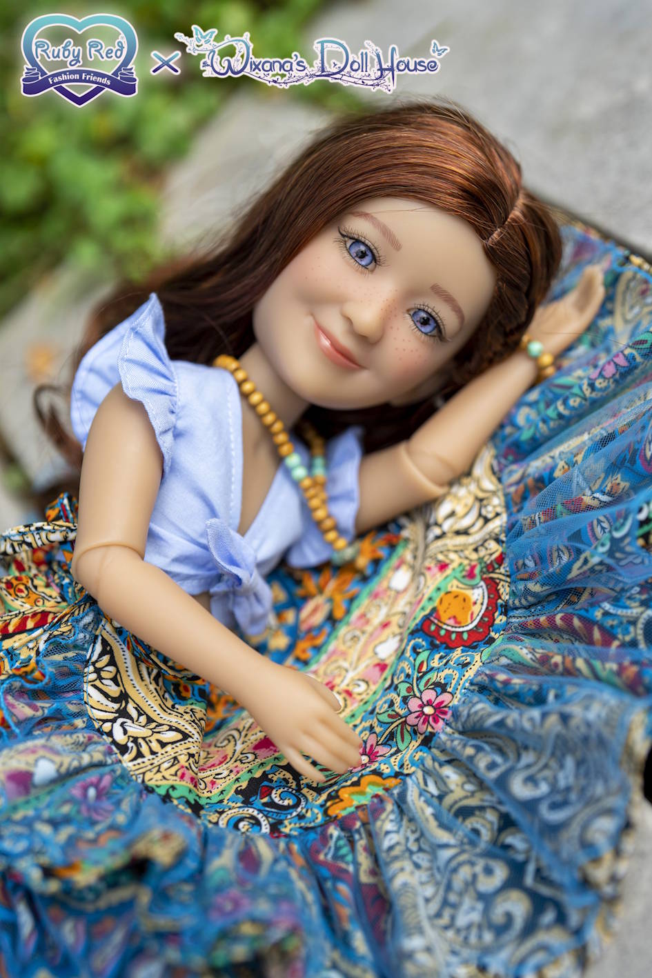 Doll with long brown hair wearing a blue dress and colorful patterned shawl.