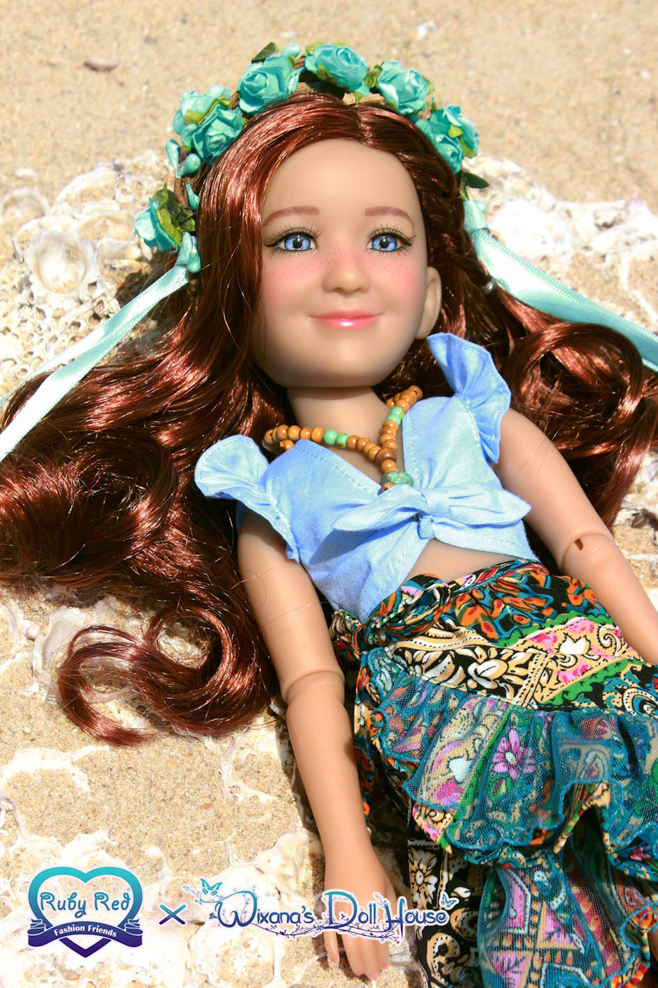 Doll with long brown hair and floral headband lying on sand, wearing a blue top and patterned skirt.