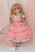 Doll in a pink dress with ruffles against a pink polka dot background