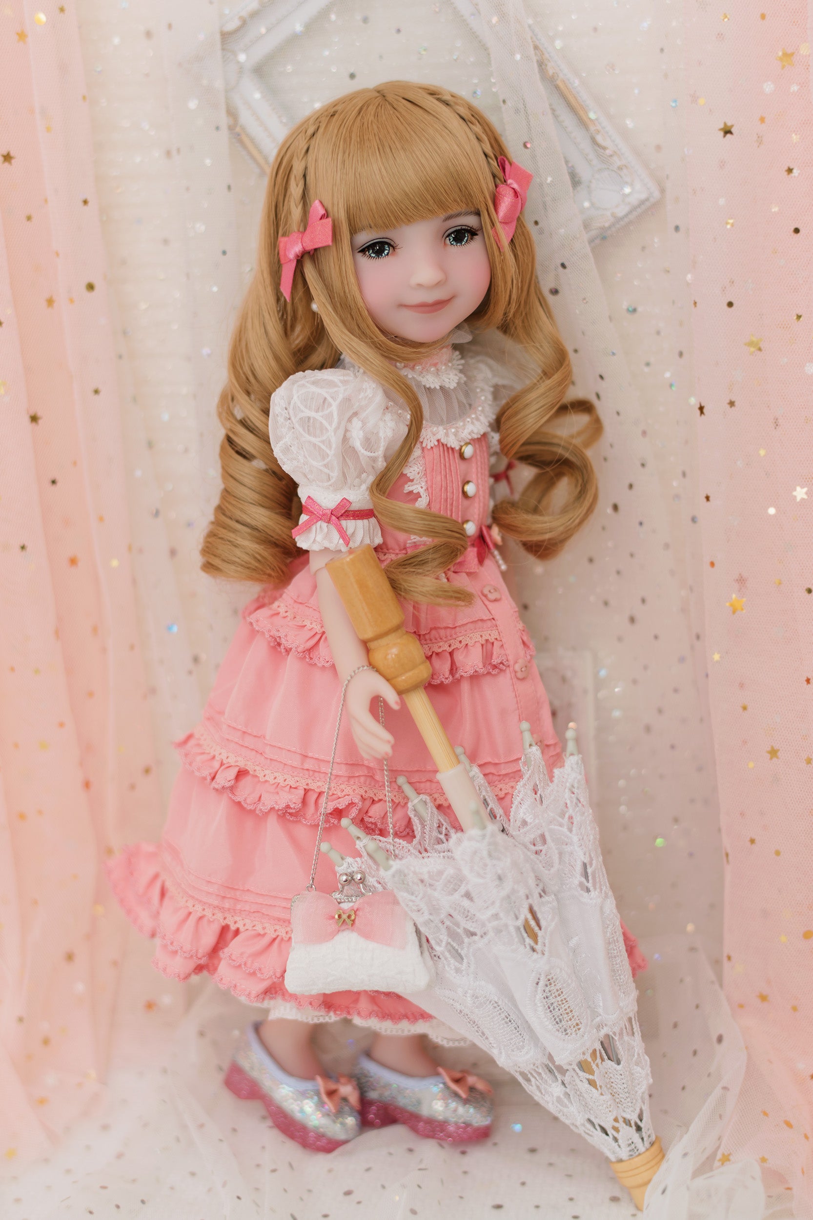 Doll in a pink dress with a white parasol against a soft pink background