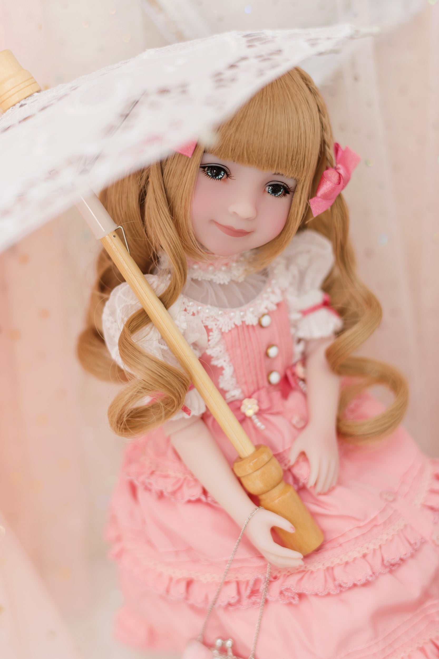  Doll in a pink outfit holding an umbrella on a light background
