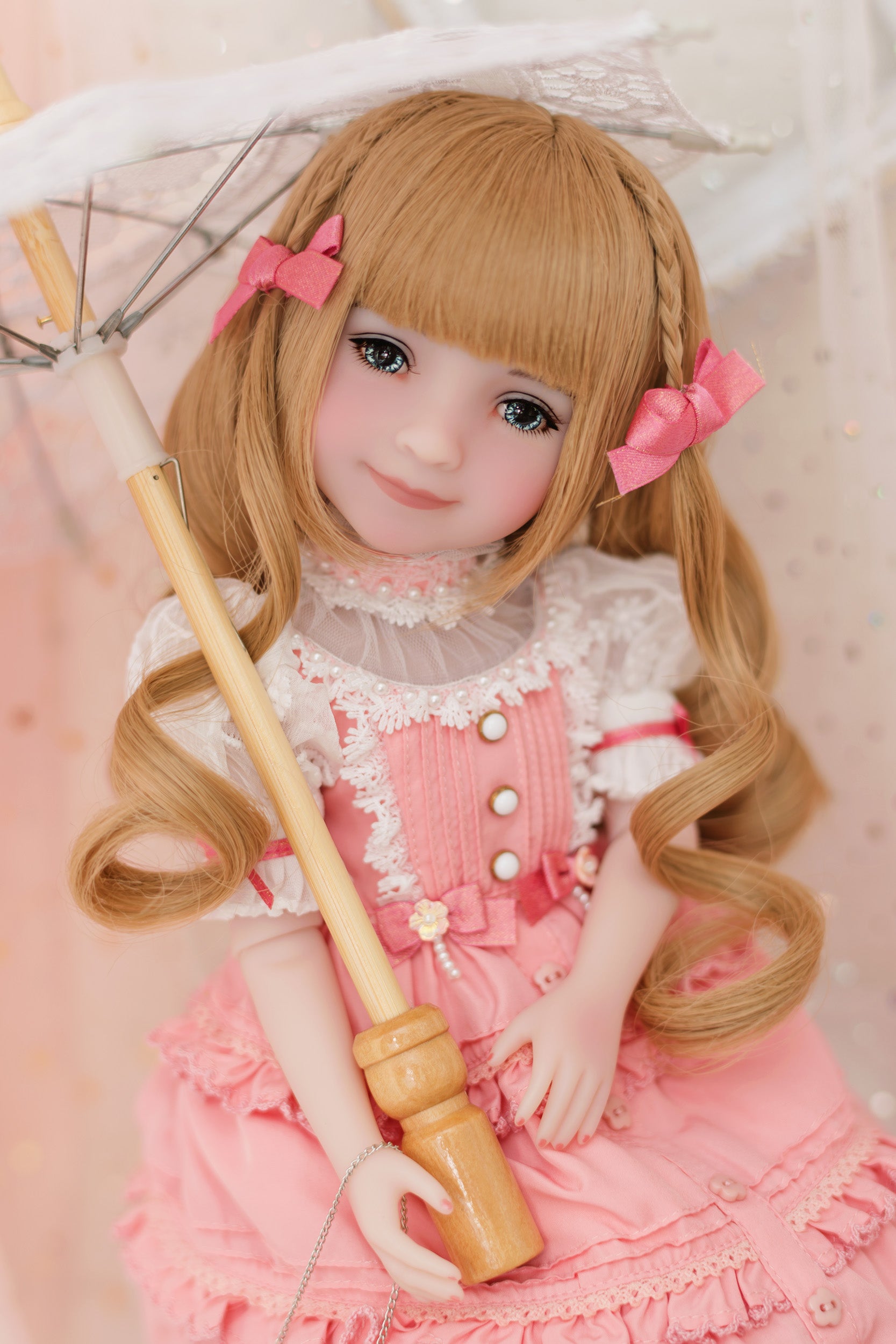 Doll in a pink outfit with a white lace collar holding an umbrella.