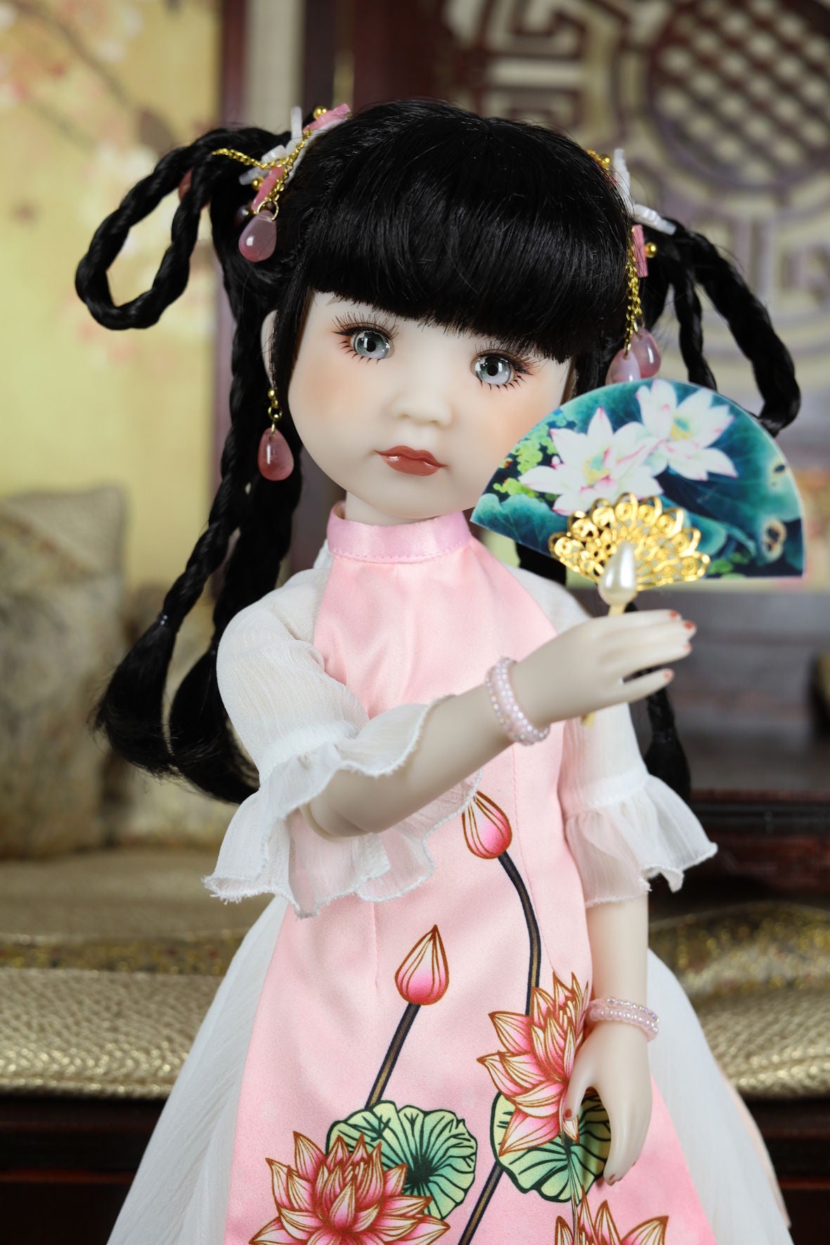 Traditional Chinese doll holding a fan with floral design