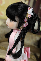 Doll with braided hair and decorative hair accessories in a blurred indoor setting