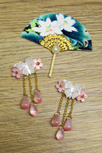 Traditional hairpins with floral and teardrop designs on fan in a wooden background.