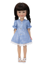 Doll wearing a blue dress with white buttons on a white background