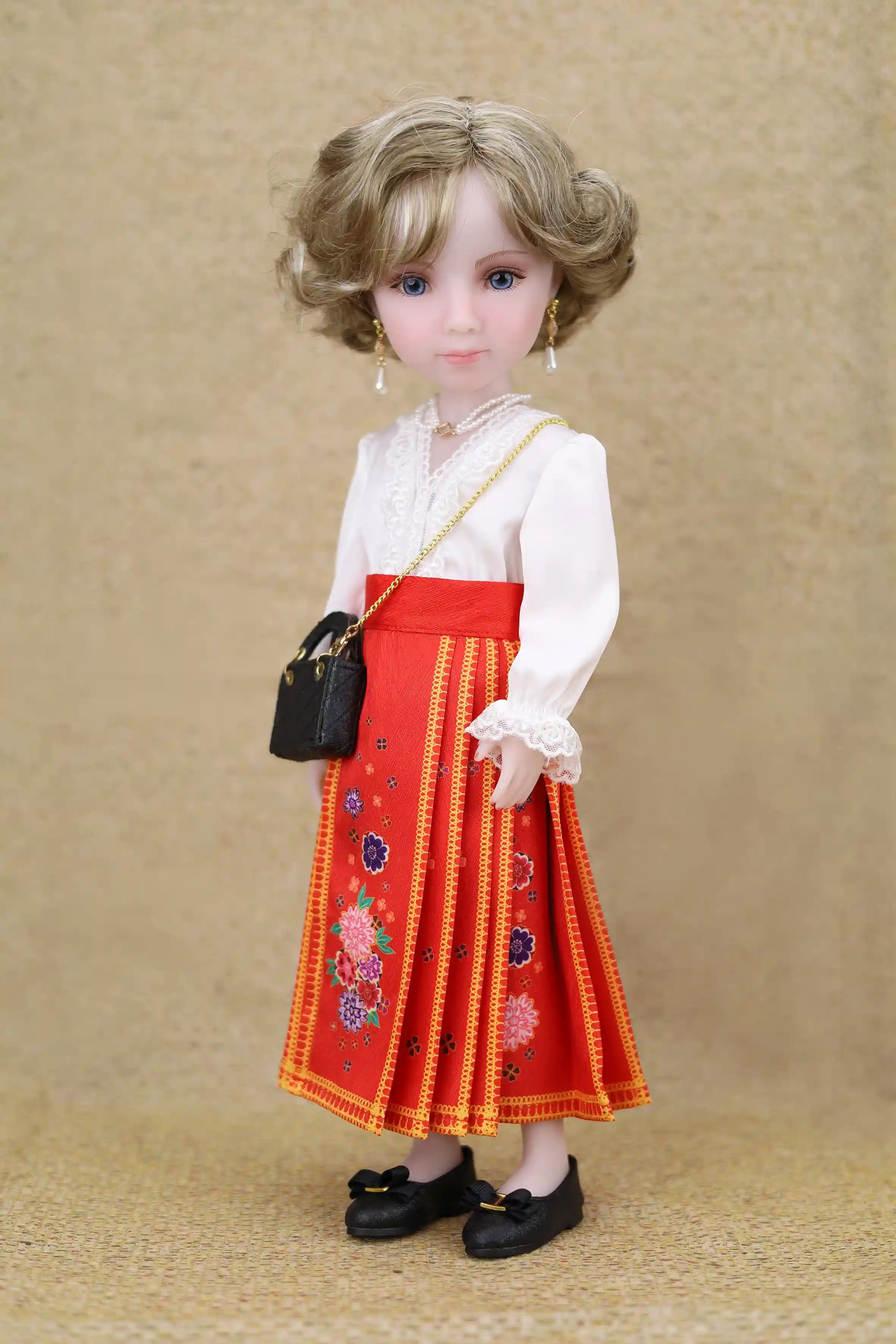 Doll wearing a red embroidered skirt and white blouse with a black handbag on a beige background