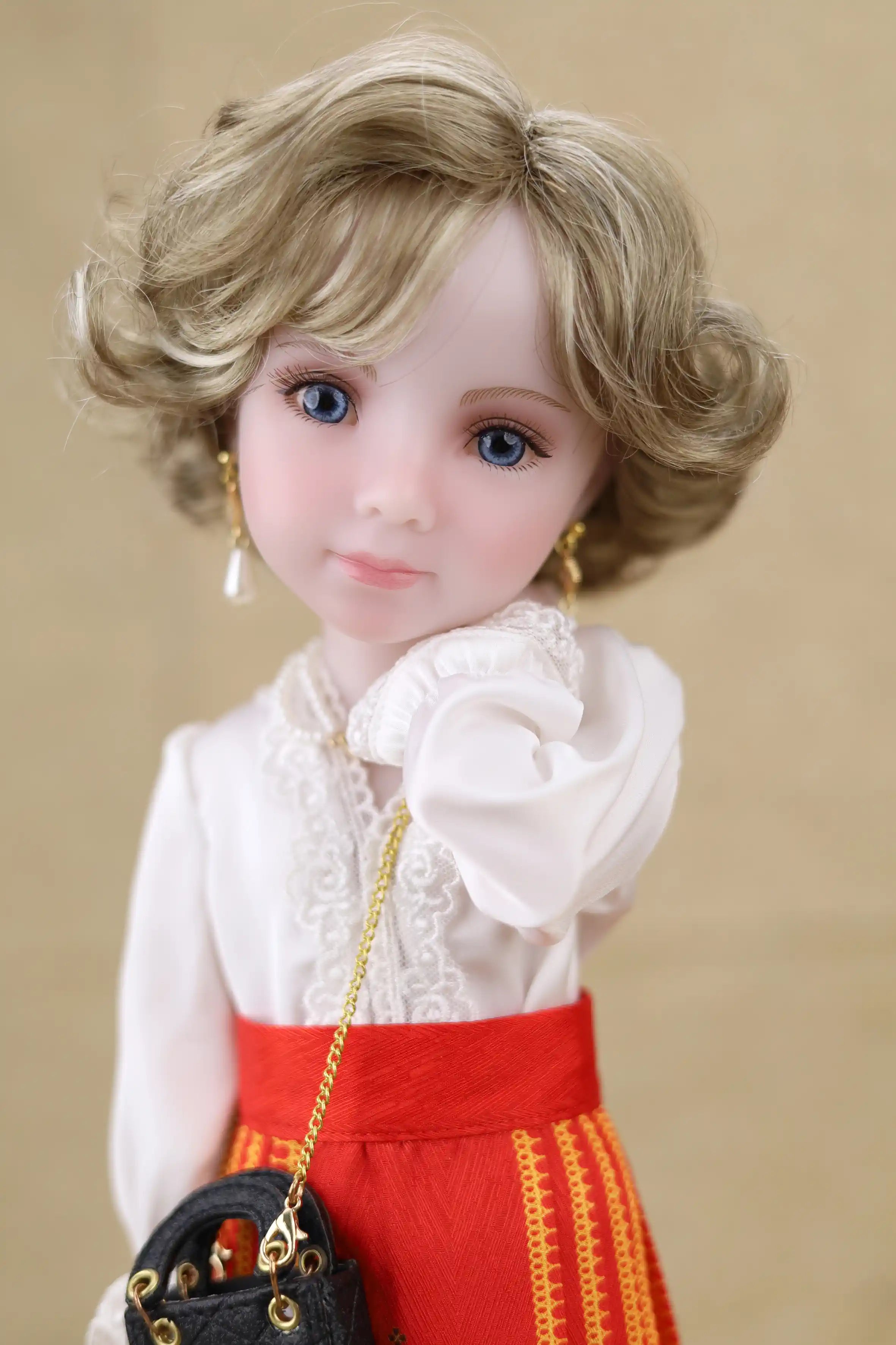 Doll with blonde hair and blue eyes wearing a white blouse and red skirt against a beige background