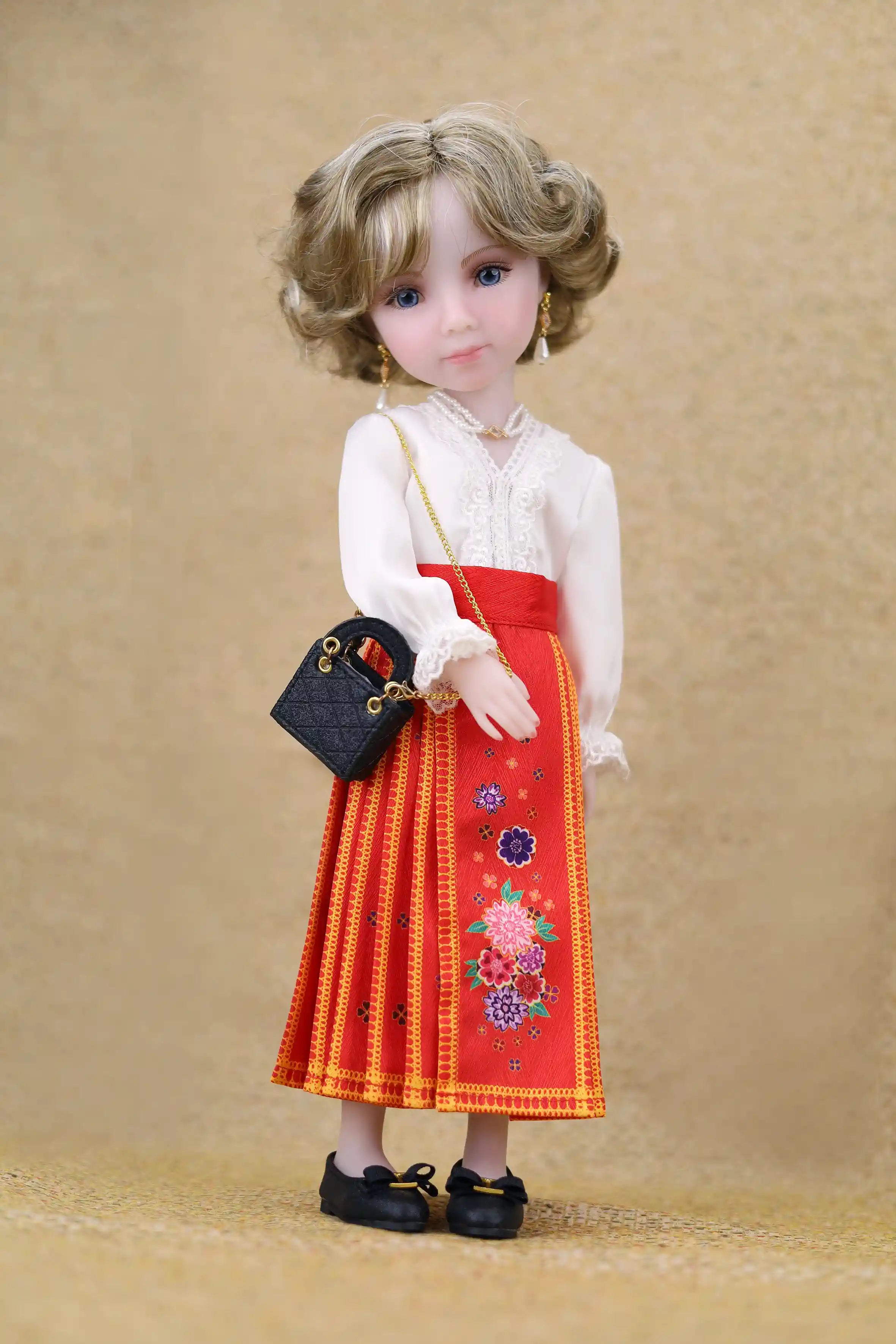 Doll wearing a white blouse and red skirt with floral embroidery on a beige background