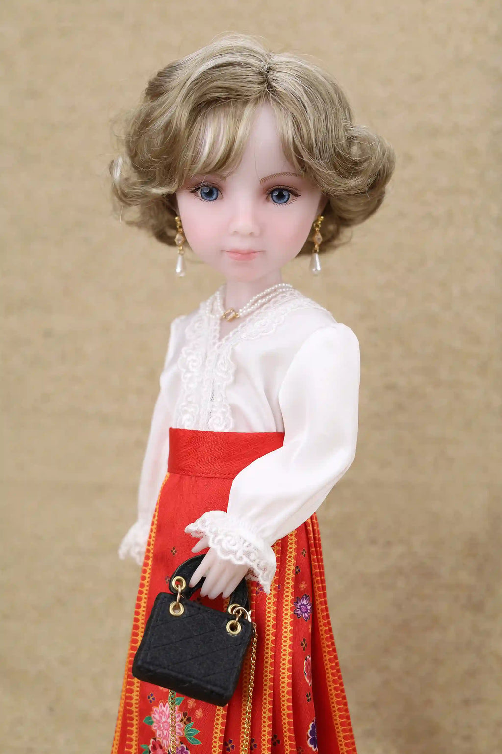 Doll wearing a white blouse and red skirt with a black handbag on a beige background