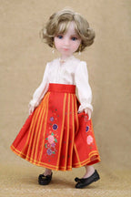 Doll wearing a red dress with floral embroidery on a beige background