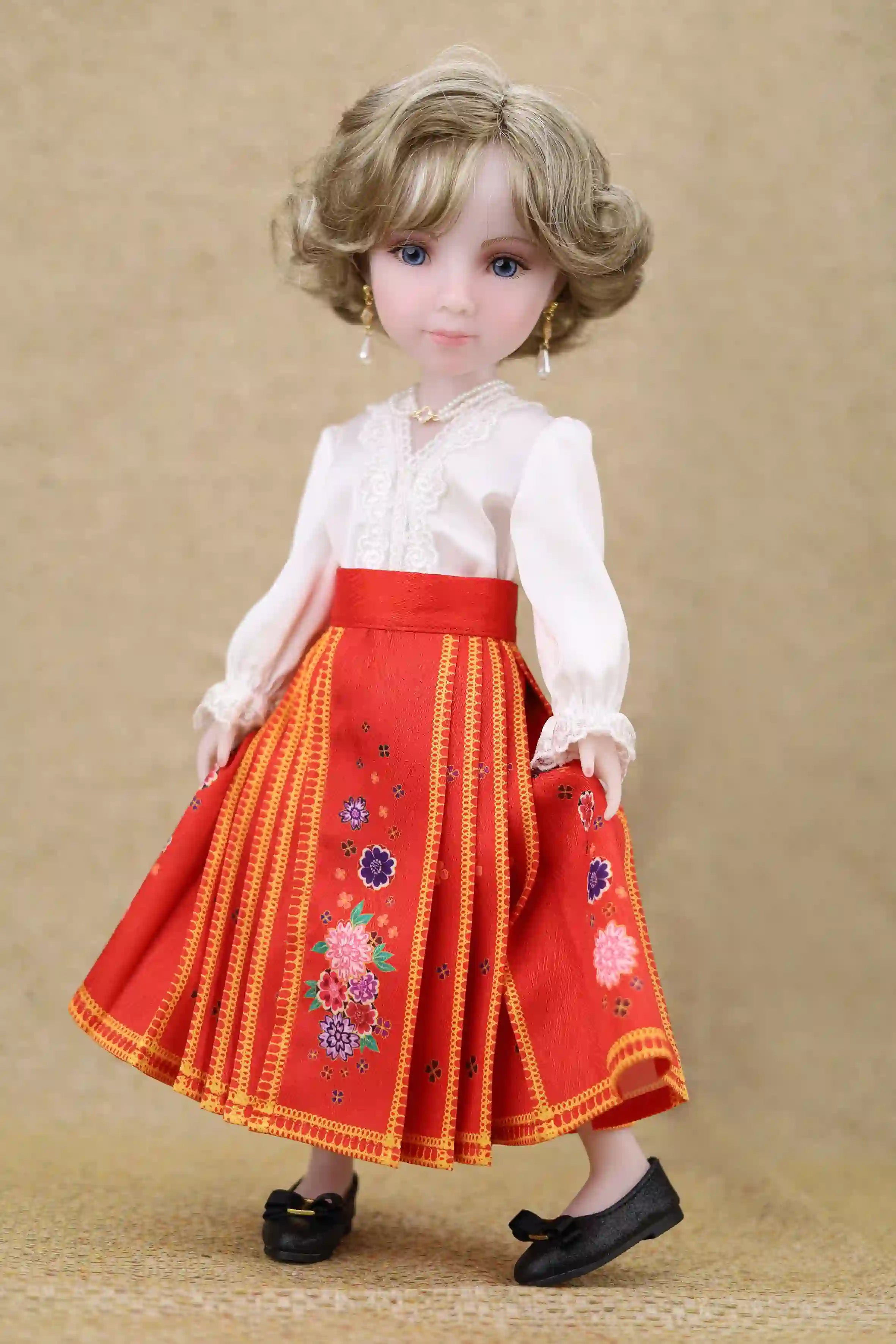 Doll wearing a red dress with floral embroidery on a beige background
