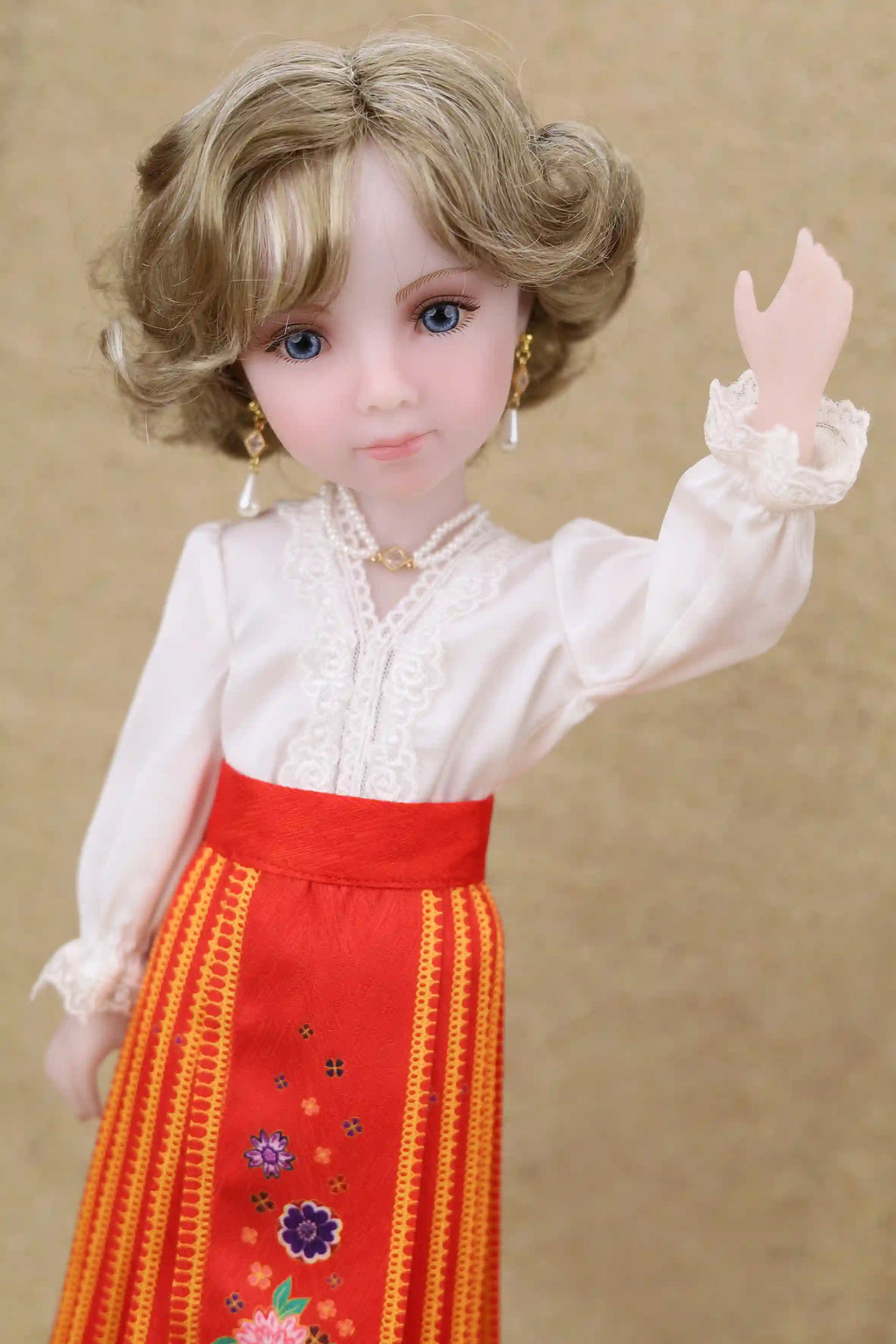 Doll wearing a white blouse and red skirt with floral patterns on a beige background