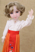 Doll wearing a white blouse and red skirt with floral patterns on a beige background