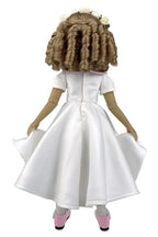 Doll wearing a white dress with a plain background