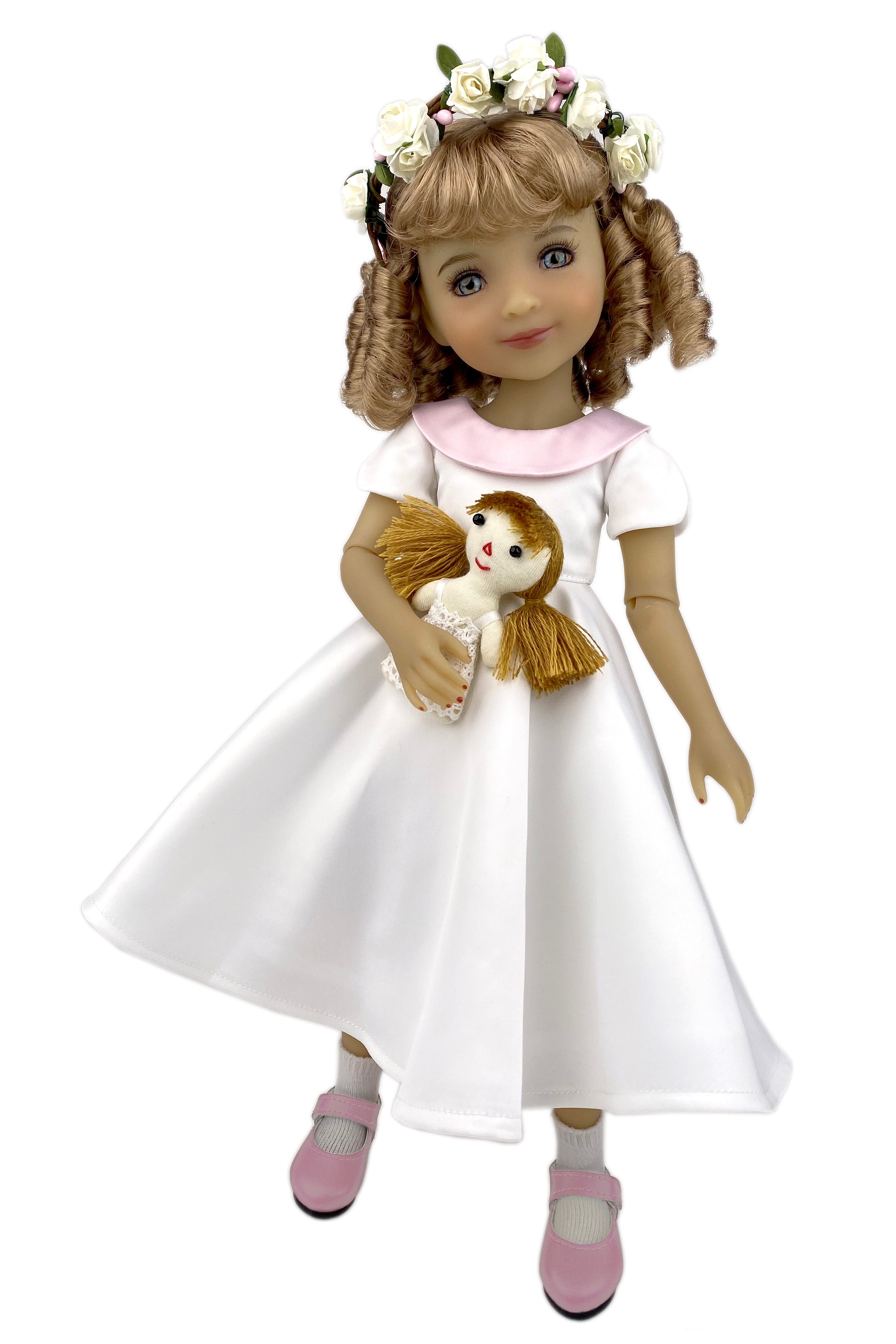 Doll in a white dress holding a teddy bear on a white background