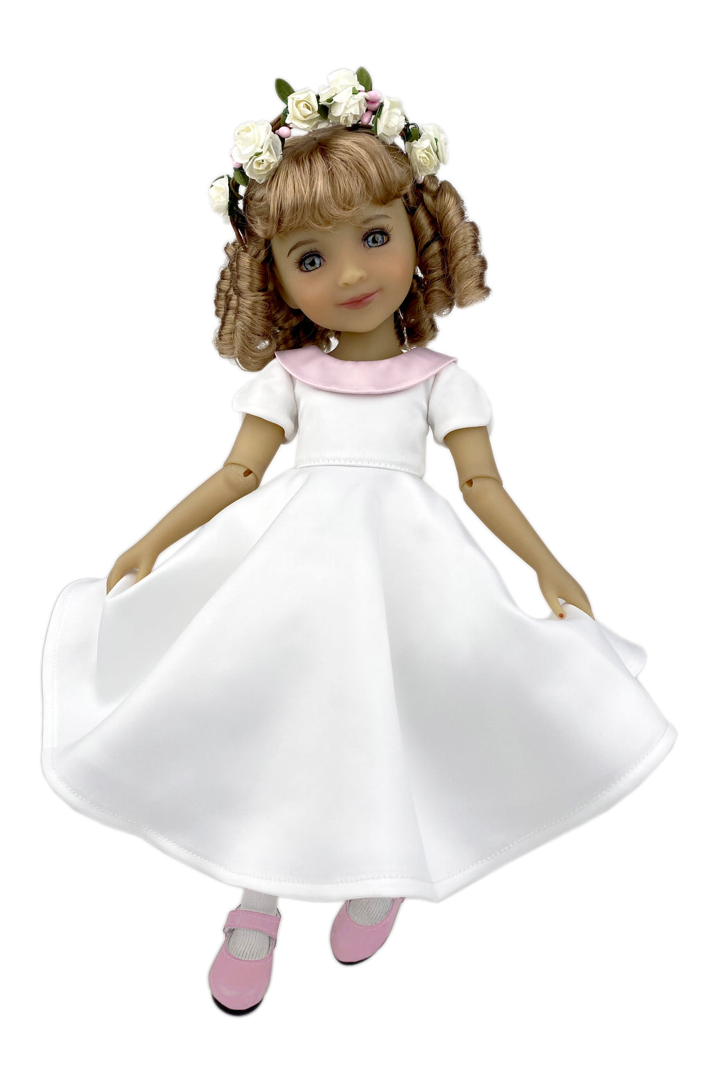 Doll wearing a white dress with a pink collar and flower crown on a white background
