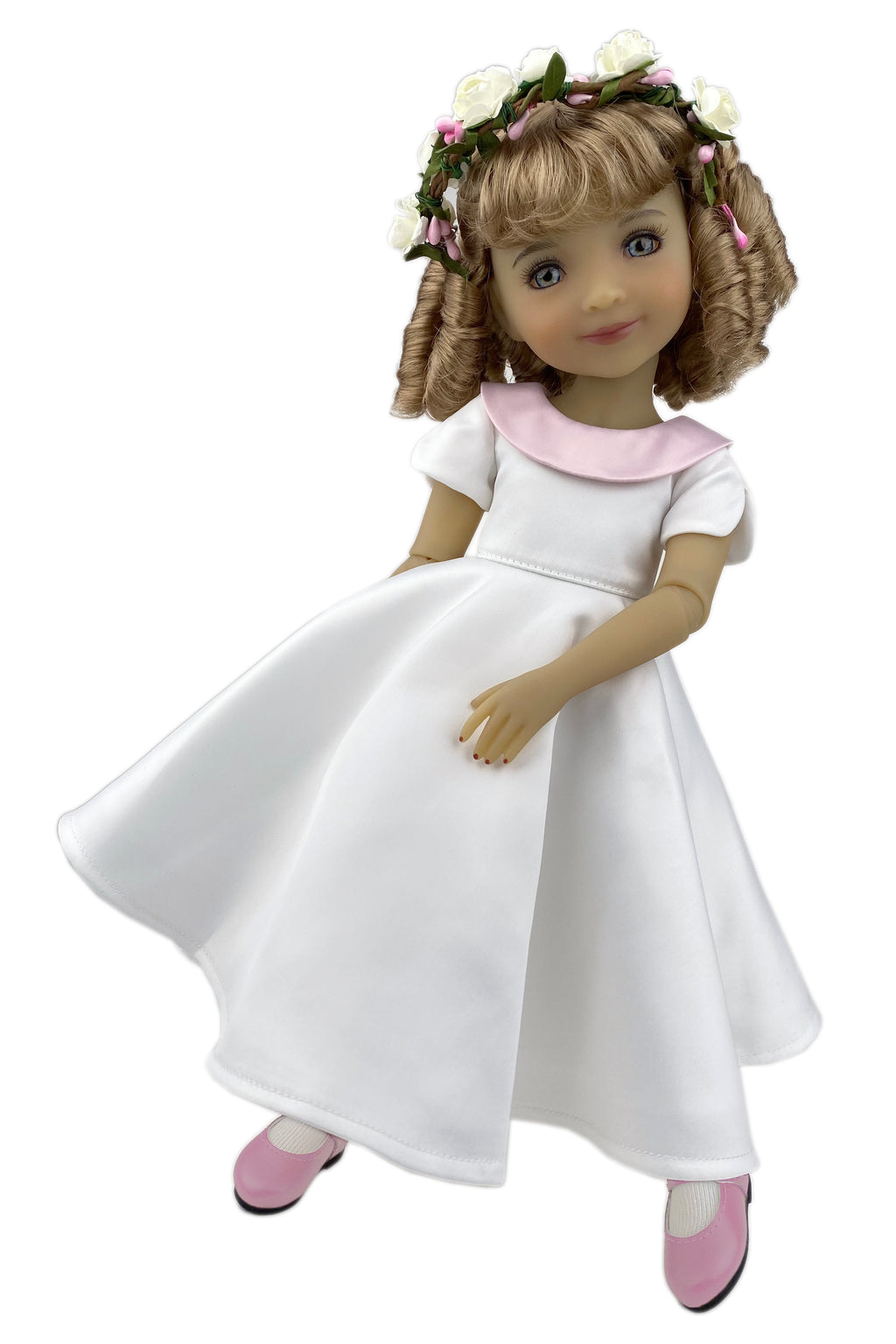 Doll wearing a white dress with a pink collar and flower crown on a white background