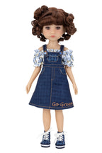 Doll wearing a denim dress with floral top on a white background