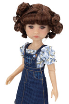 Doll with brown hair styled in buns, wearing a floral top and denim overalls on a white background.
