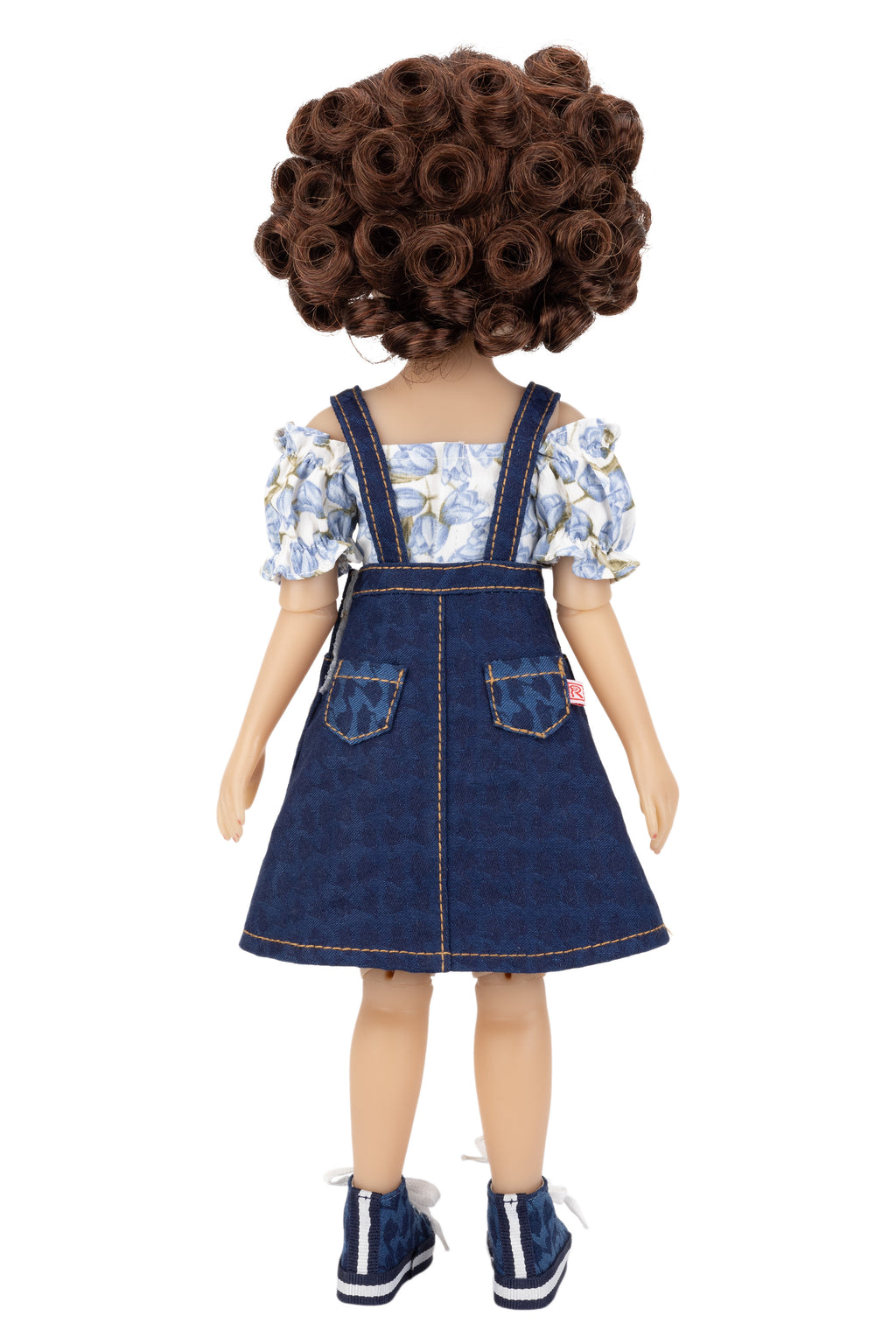 Doll wearing a floral top and denim dress on a white background