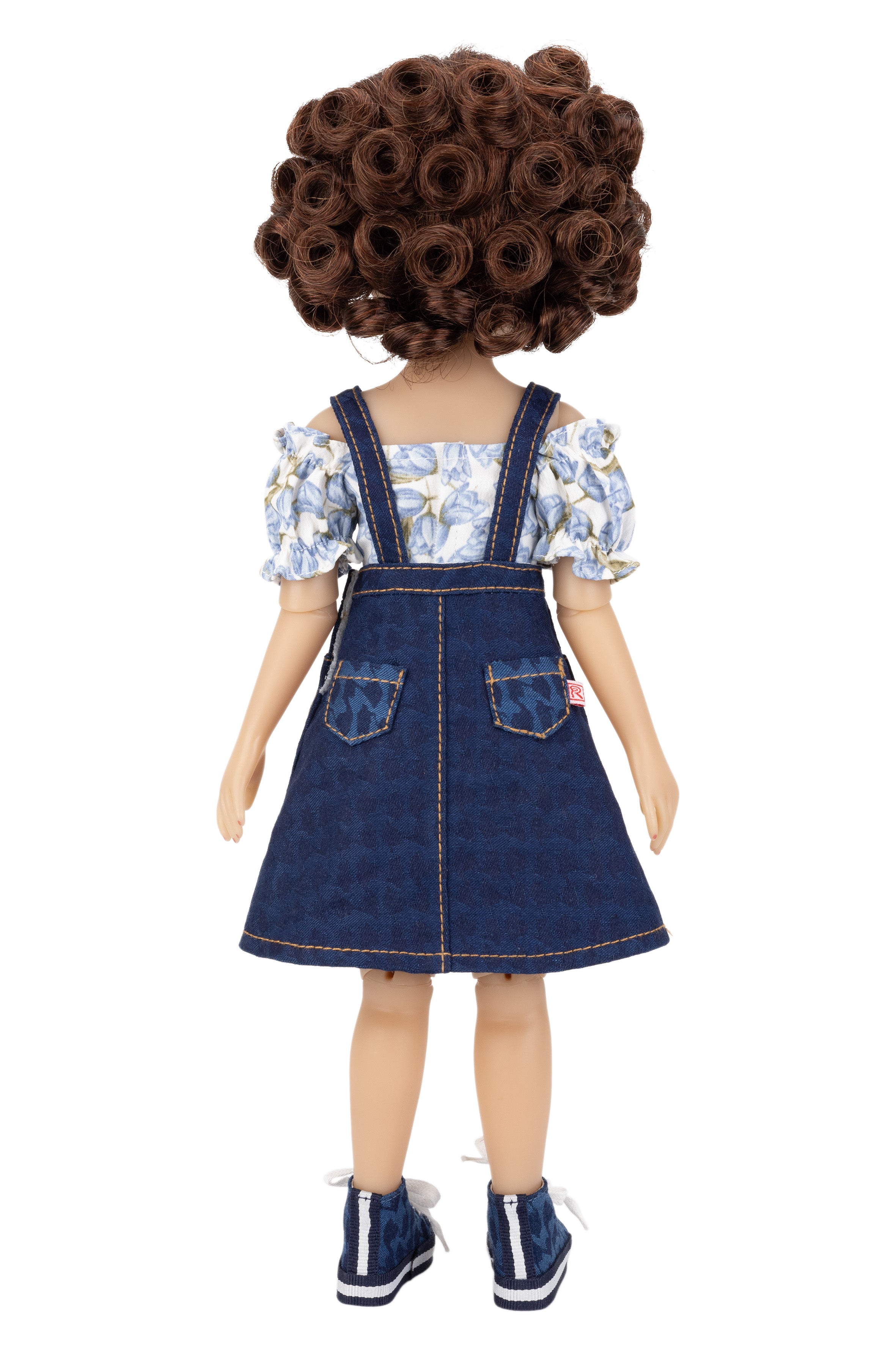 Doll wearing a floral top and denim dress on a white background