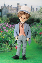 Doll in formal attire standing in a garden with a castle in the background