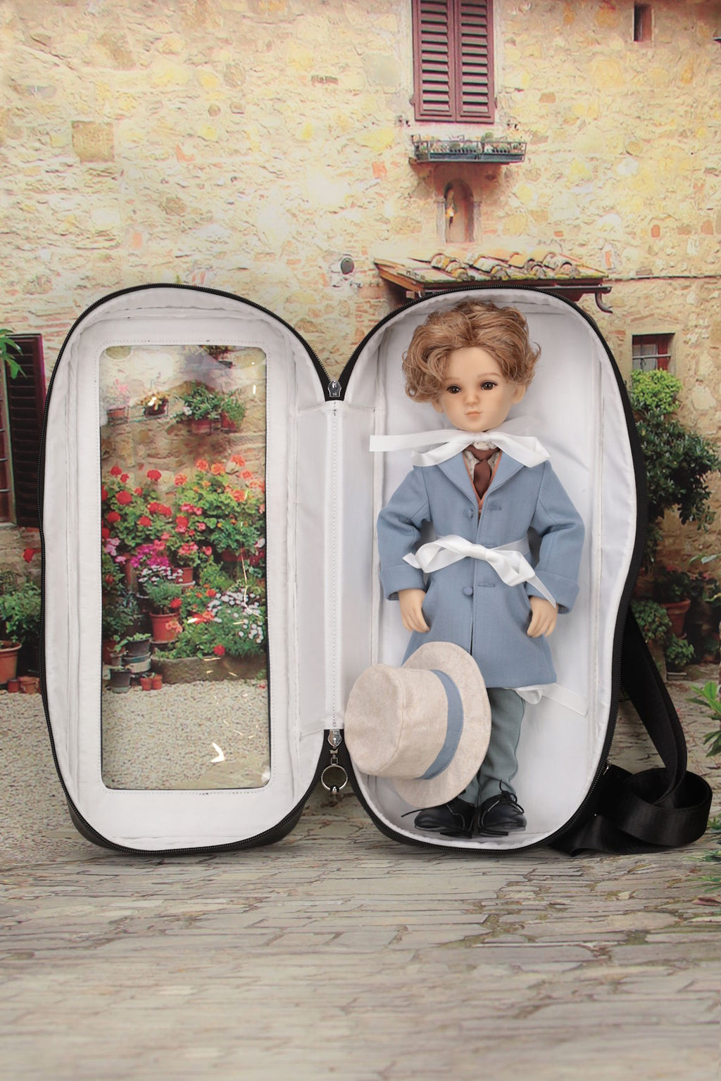 Doll in a carry bag with a scenic view on a stone path