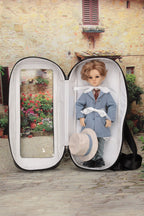 Doll in a carry bag with a scenic view on a stone path