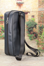 Black doll carry bag with a strap on a wooden surface with a garden background