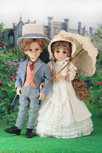 Two dolls in period clothing standing in a garden with a castle in the background