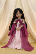 Doll in a pink and purple dress with a plain background