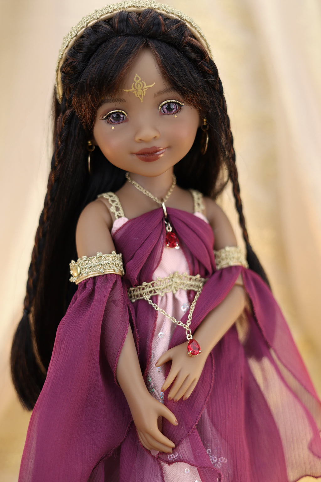 Doll in a purple dress with gold accents and jewelry against a beige background