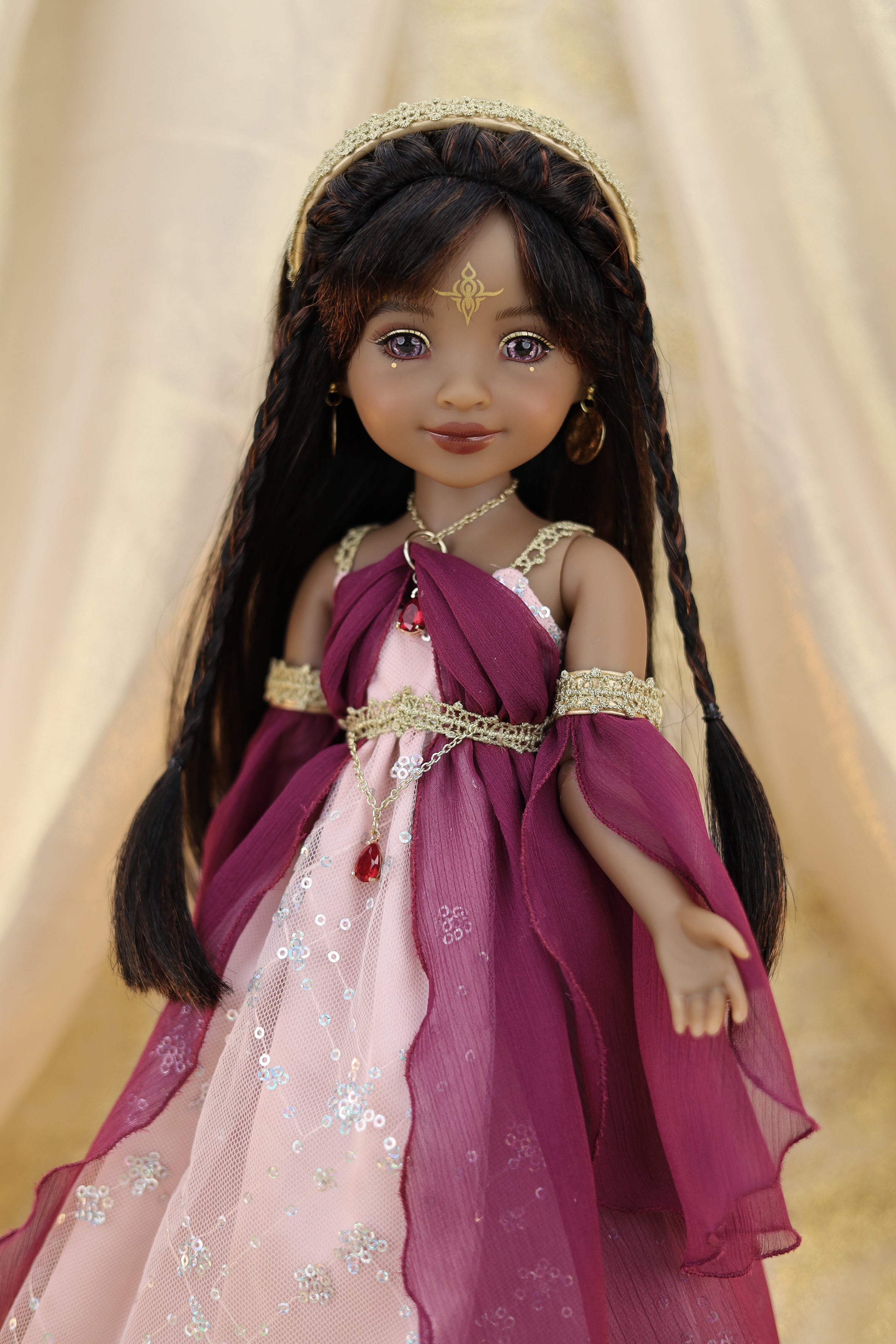 Doll in a purple and pink dress with a tiara against a beige background