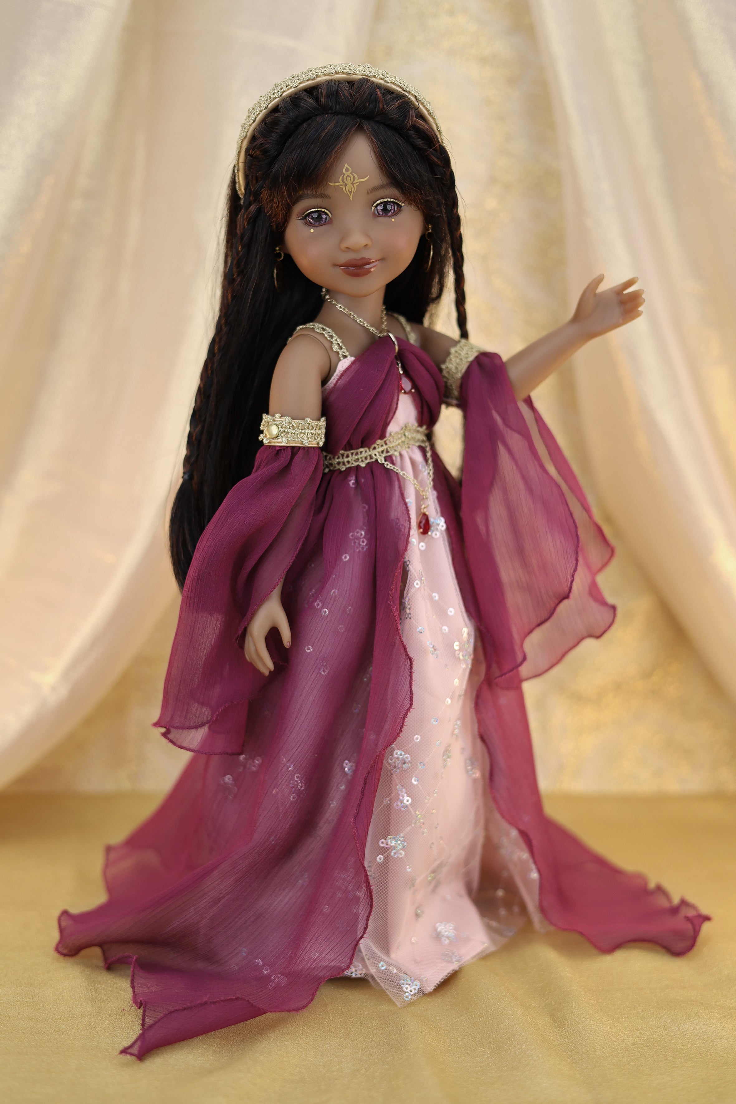 Doll in a purple and pink dress with a gold headband against a beige curtain background