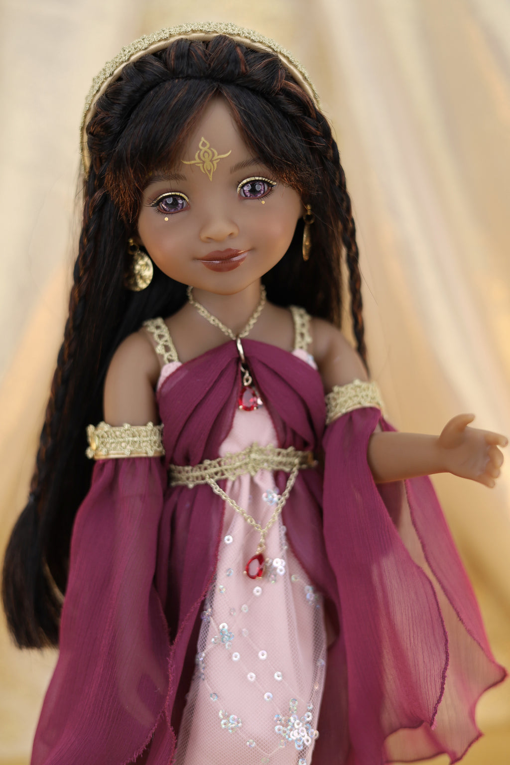 Doll in a pink and purple dress with gold accents against a beige background