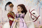 Two dolls in historical attire with a white horse against a floral background