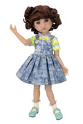 Doll wearing a blue denim dress with a yellow shirt on a white background